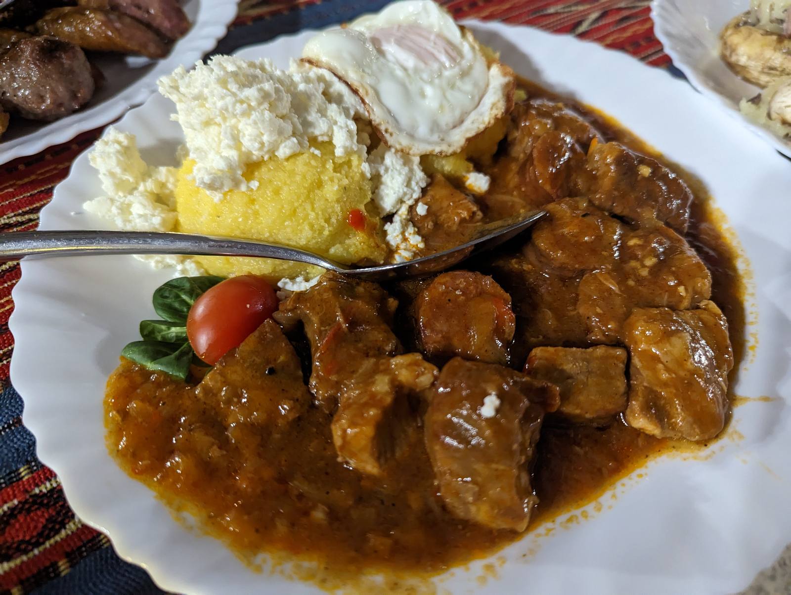 ルーマニアの伝統料理トキトゥラ（豚肉の煮込みと目玉焼き・チーズ）
