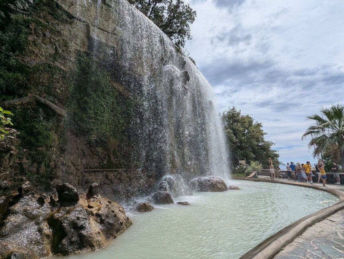 城の丘公園内の人工滝 岩肌を流れ落ちる水としぶきを浴びる観光客