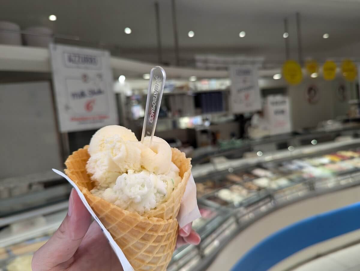 コーンに盛られた2種類のジェラート 背景にジェラート専門店のショーケース