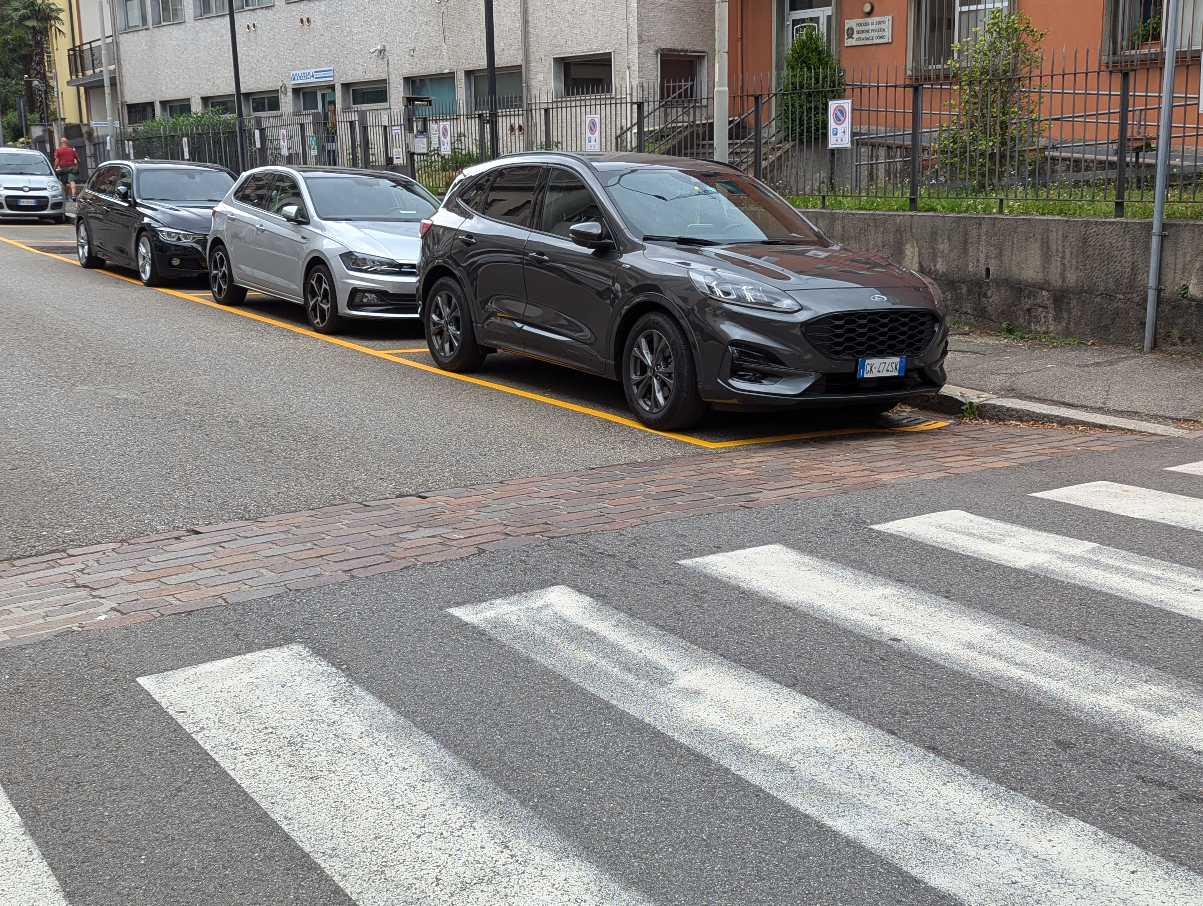 イタリア・コモの黄色い路肩ラインが引かれた駐車スペースと警察署前の車列