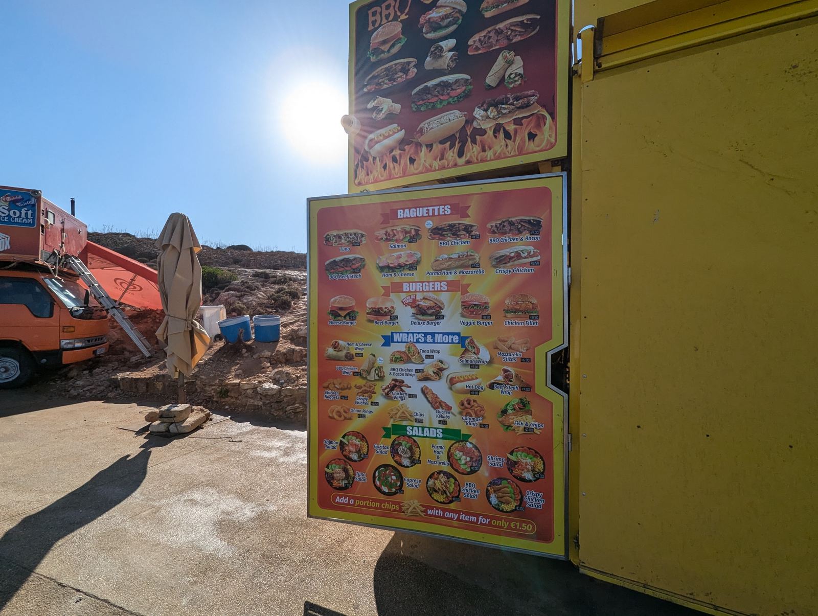 フードトラックのメニュー看板。バゲット、バーガー、ラップ、サラダの写真と価格が並ぶ