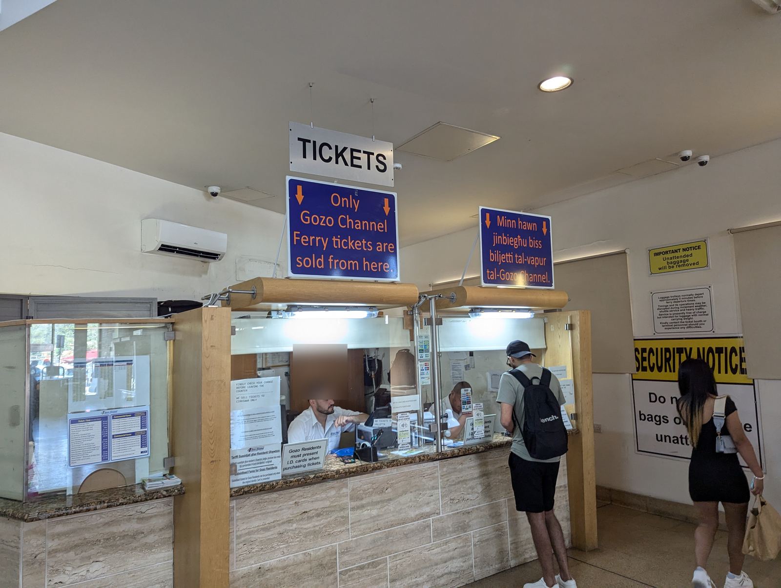 ムジャール港ターミナル内のチケットカウンター。頭上に青い案内看板が下がっている