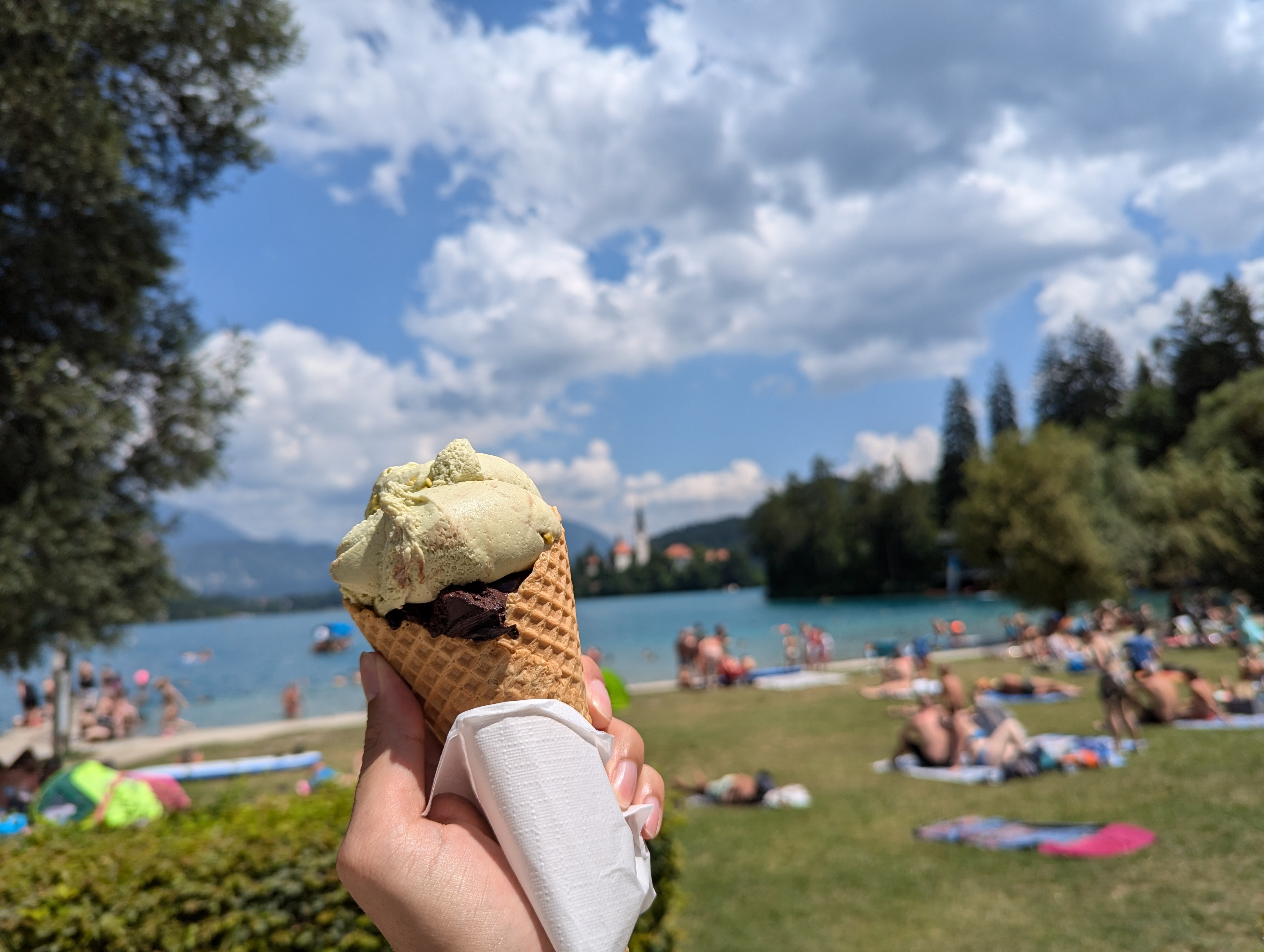 ブレッド湖畔のビーチを背景に持つピスタチオとチョコレートのジェラート