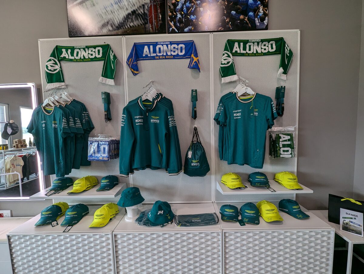 アストンマーティンのチームウェアとFERNANDO ALONSOマフラーが並ぶ売り場