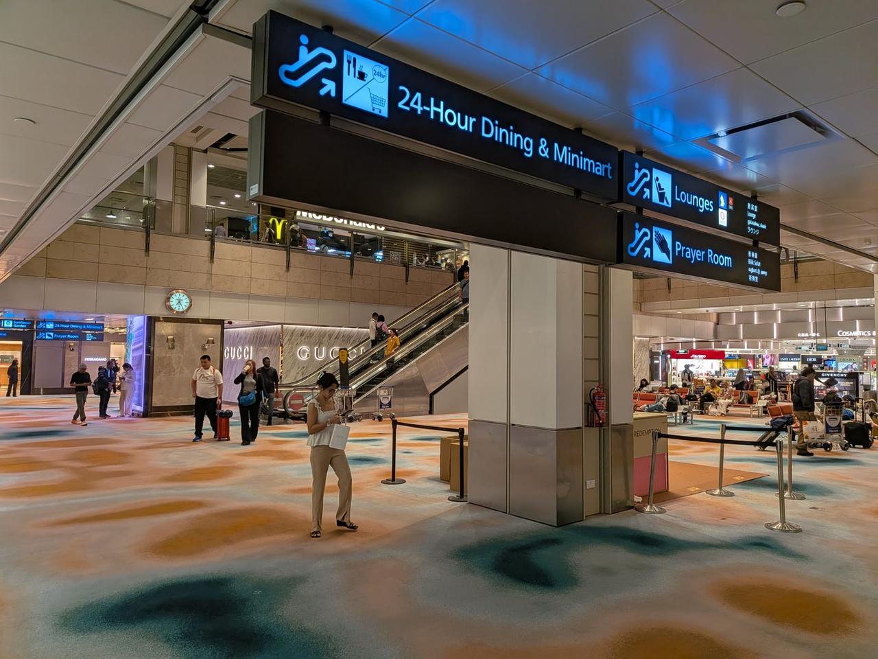 チャンギ空港T2の「Lounges」案内サインとラウンジへ上がるエスカレーター